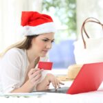 A woman wearing a Santa hat shopping online.